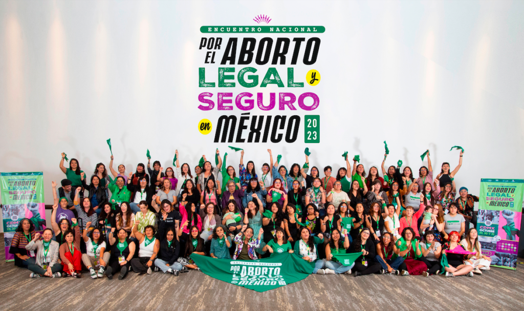 Banner que está ilustrado con la fotografía en plano general de un grupo numeroso de mujeres que sostienen pañuelos verdes aborteros