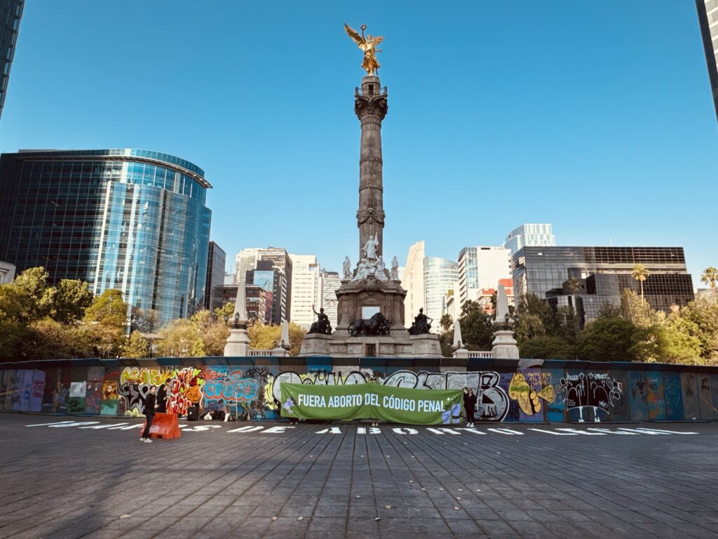 Banner que está ilustrado con la fotografía en plano general del Ángel de la independencia, frente a él unas mujeres sostienen una manta que dice "Fuera aborto del código penal"