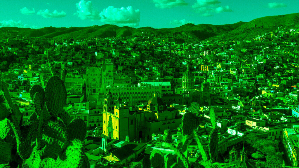 Banner que está ilustrado con la fotografía panorámica de Guanajuato. Se ven nopales y casas entre los cerros. La imagen está intervenida con un filtro verde.